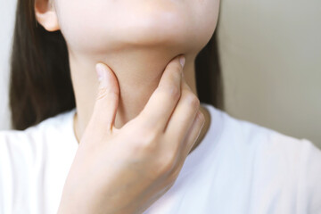 sore throat pain. Closeup of young woman sick holding her inflamed throat using hands to touch the...