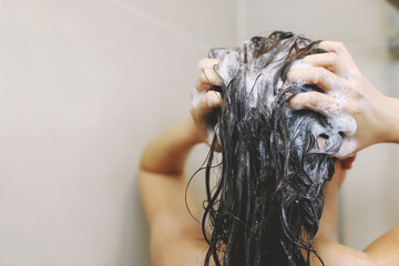 Woman is washing her hair with shampoo.
