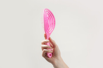 Young woman holding pink detangler hair brush, studio shot