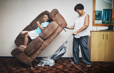 Grandma, boy and vacuum in home portrait, play games and lazy to clean for housework. Grandparent,...