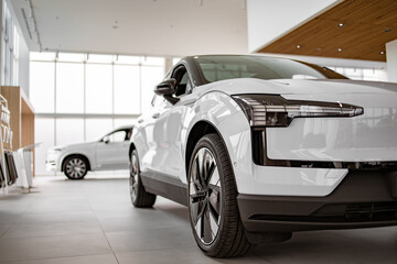 Front part of brand new modern white car, parked at showroom. Reflection in led headlights of...