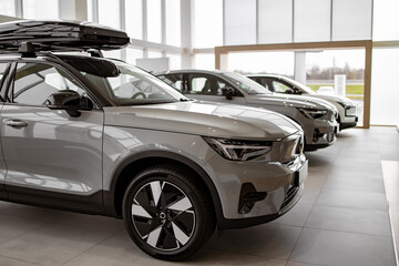 Side view of new SUVs car parked in row indoors modern light dealership showroom.