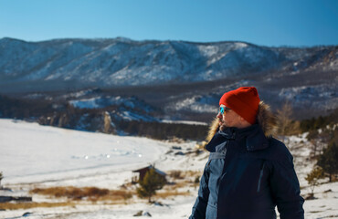 Traveller man in a blue winter jacket ad red cap in the woods. Sandy bay, Baikal lake, winter time