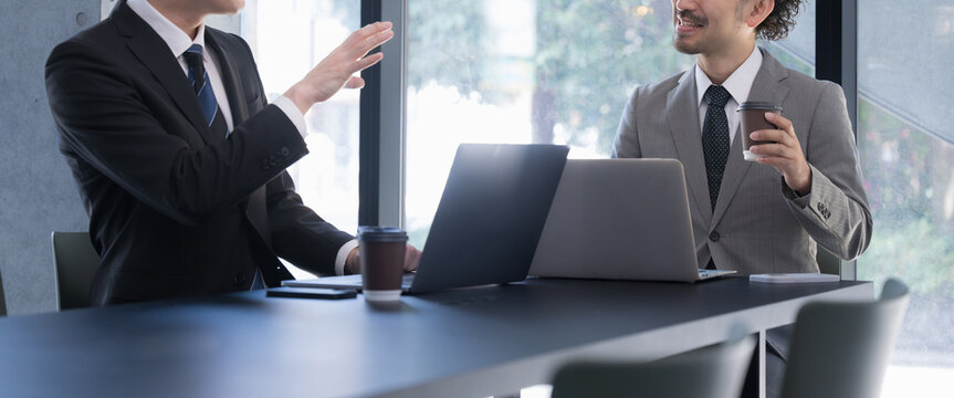 Two men meeting at a computer by a window Banner of a subordinate making a proposal for a project or job and his boss listening Banner without a face