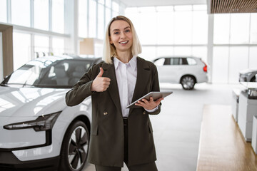 Attractive young woman standing in front of car with digital tablet. Professional salesperson...