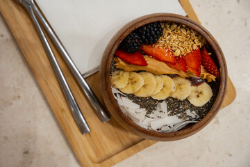 an acai bowl with complete toppings of mixed berries, oats, bananas, dried coconut and chia seeds