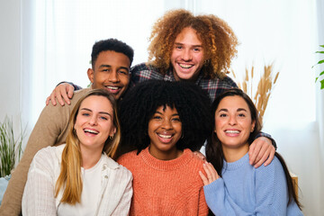 Group of multiracial happy friends looking at camera and smiling at home.