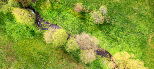 A small river from above in a meadow panorama
