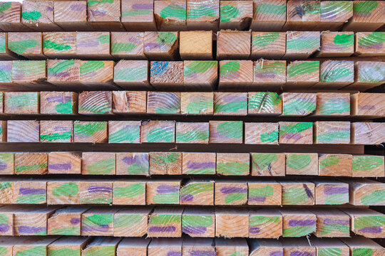 Stack of colorful wooden planks construction in the warehouse in industry. Stacks with pine lumber, wood harvesting shop, Stacked wooden boards for construction.	