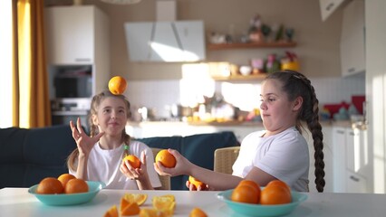children group juggle oranges fruit food in the kitchen. healthy eating concept. children girls eat...