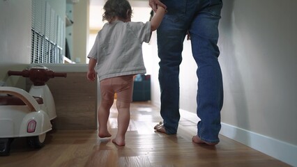 baby first steps with dad. happy family a kid dream concept. dad and baby daughter walk along the...