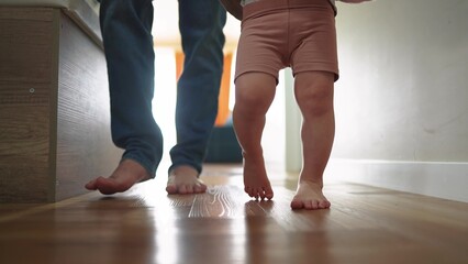 baby first steps with dad. happy family a kid dream concept. dad and baby daughter walk along the corridor of the house indoors. dad and daughter care, hold hands lifestyle, walk, take first steps
