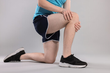 Man suffering from leg pain on grey background, closeup