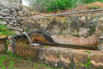 stream of water coming out of the pipe, in a stone tank