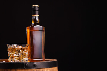 Whiskey in glasses and bottle on wooden barrel against black background, space for text