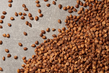 Close-up of a pile of buckwheat grains on the grey background.