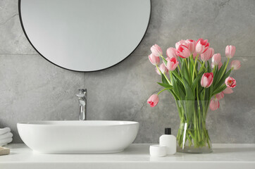 Vase with beautiful pink tulips near sink in bathroom