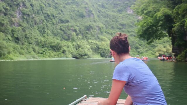 Woman with her back on a boat in Vietnam in Tam Coc exploring the wonders of the area and nature. Solo woman travel adventures in Southeast Asia, discovering new cultures and adventures.
