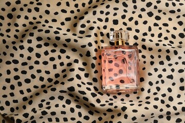 Luxury perfume in bottle on fabric with leopard pattern, top view