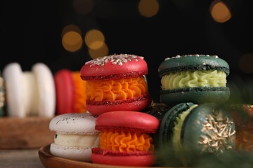 Beautifully decorated Christmas macarons on table against blurred lights, closeup