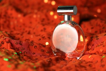 Luxury perfume in bottle on red fabric with sequins, closeup
