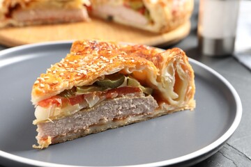 Piece of tasty homemade pie with filling on dark grey table, closeup