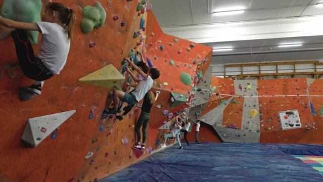 A team of children aged 10 years old are engaged in extreme sports on the indoor climbing wall. Brave children climb the wall, they are not afraid of heights. The desire to be the first. 4k footage