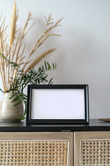 Fototapeta premium small black frame to put photos that has a white background, in a horizontal position, on top of a modern piece of furniture