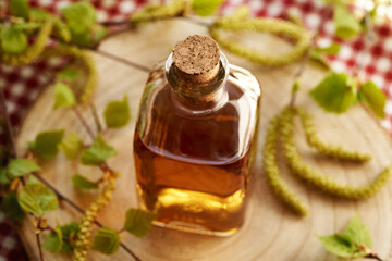 A bottle of herbal tincture with birch branches with young leaves and catkins harvested in spring