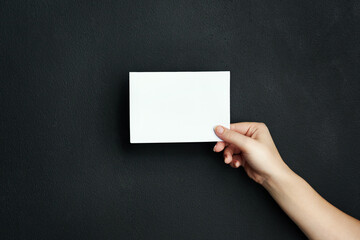 Hand, studio and blank paper with mockup space for sale, promotion offer or information about us. Closeup, signage or person with placard for news, announcement or logo advertising on dark background