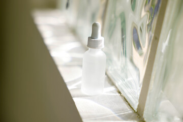 A clear and transparent beauty serum place near in the window with sunlight reflection