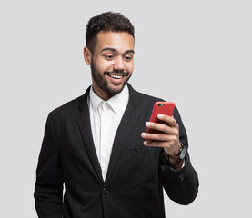 Portrait of handsome cheerful smiling young man using smartphone isolated on gray background. Laughing joyful men with mobile phone studio shot - 786191729