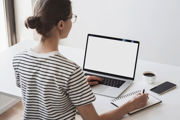 Young woman using laptop computer with blank empty mockup screen. Business woman working at office. Freelance, student lifestyle, e-learning, shopping online, web site, technology concept