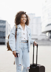 Beautiful woman tourist with suitcase luggage standing in a city. Smiling mixed race girl going on travel. Business travel, student lifestyle, people, tourism concept - 786194905