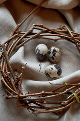 Three quail eggs are nestled in a Christmas ornament crafted from natural materials, including branches and twigs, resembling a wreath