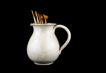 Earthenware Wine Jug with Artists Paint Brushes Isolated on a Black Background - 786196540