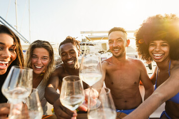 Multiracial friends having fun at boat party during summer vacation - Happy people cheering with champagne inside yacht at sunset - Travel and holidays concept - Main focus on african man face - obrazy, fototapety, plakaty
