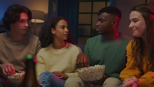 Black guy holding bowl with popcorn and telling friends joke