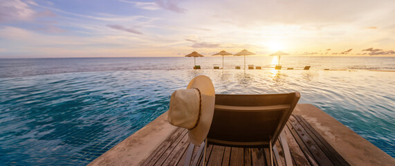 beach vacation, panoramic infinity pool with deckchair and hat in luxury hotel resort