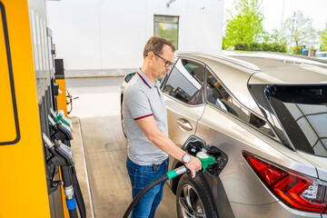 The driver fills up expensive gasoline in self-service filling station in Europe