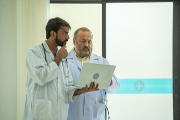 Two senior doctor hold clipboard document file of patient record talking discussion about treatment guidelines. Men surgeon doctor advice assistance expertise for comprehensive care team.