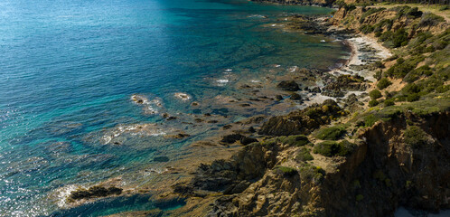 Aerial view of a rocky beach near Porto Flavia in southern Sardinia, Italy. The sea is crystal clear, clean and with colors ranging from blue to turquoise.