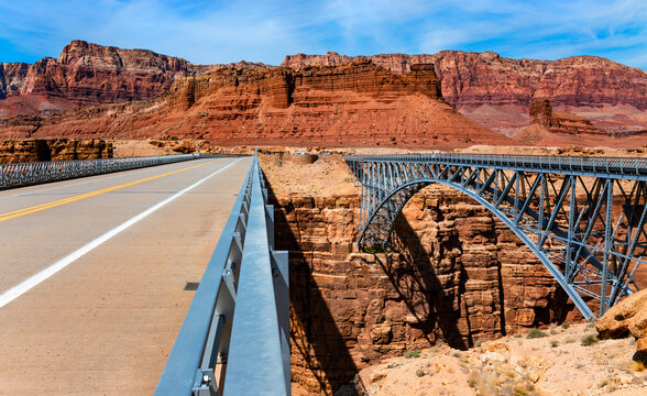 Twin spandrel arch bridges over Marble Canyon washed out by Colorado river called new and historic “Navajo Bridge“. Tall majestic steel constructions from 1929 and 1995 build next to each other.