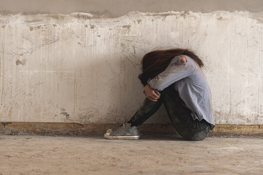 depression sad alone woman sit in dirty abandon building after raped violence against by bandit. Raped girl sit and cry in scared depressed emotion.