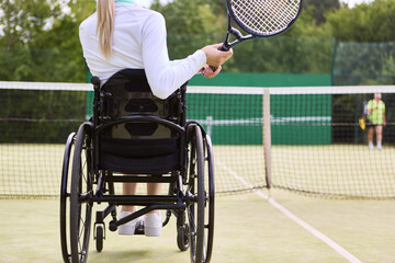 Female athlete in wheelchair playing tennis on a sunny day - obrazy, fototapety, plakaty