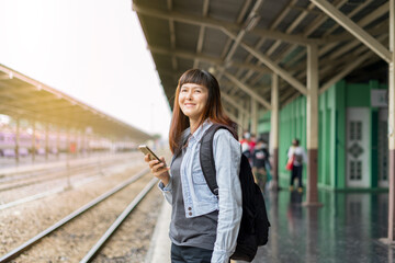 Asian woman waiting the train at train station for travel. Backpack traveler using map on...