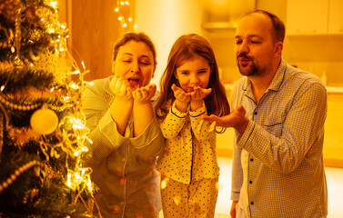 Cute little girl with her parents will blow away festive confetti. Husband and wife with their...