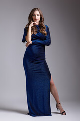 Portrait of young pretty pregnant woman on gray studio background. Female in blue sequin dress.