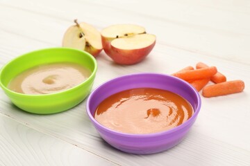 Baby food. Purees of apples and carrots in bowls on white wooden table