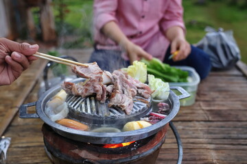 Left hand holds chopsticks Take the pork and other meat and place it on a very hot grill pan. The fresh vegetables are boiled in the pan with the soup. Thai barbecue Grill Pork on hot pan buffet.
